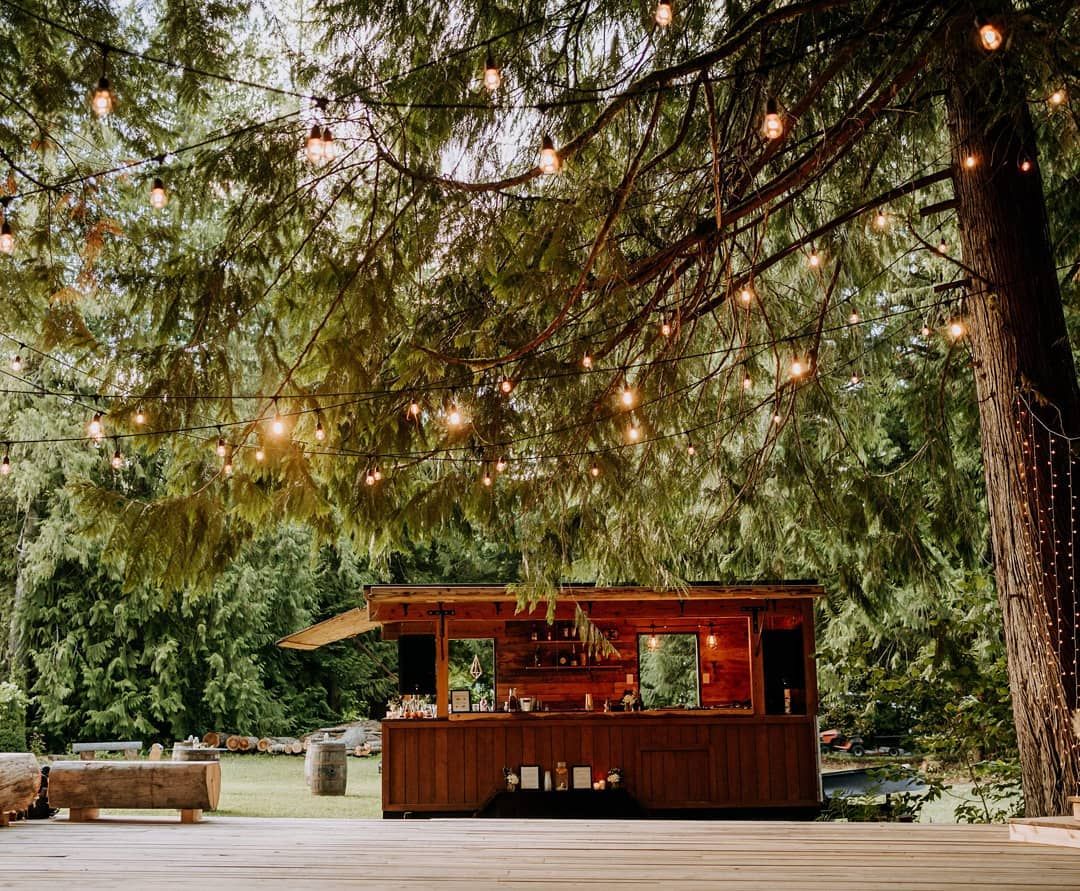 The timber trailer in a forest clearing under string lights