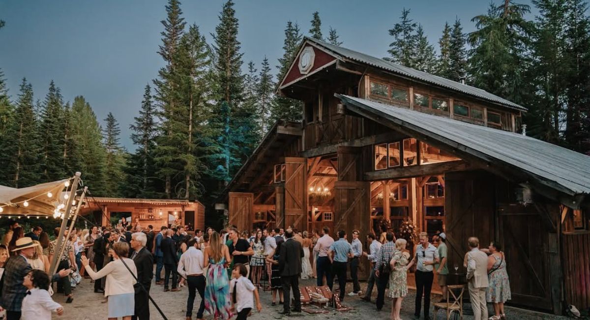 Wedding guests outside a timber barn with the Boombox bar behind them